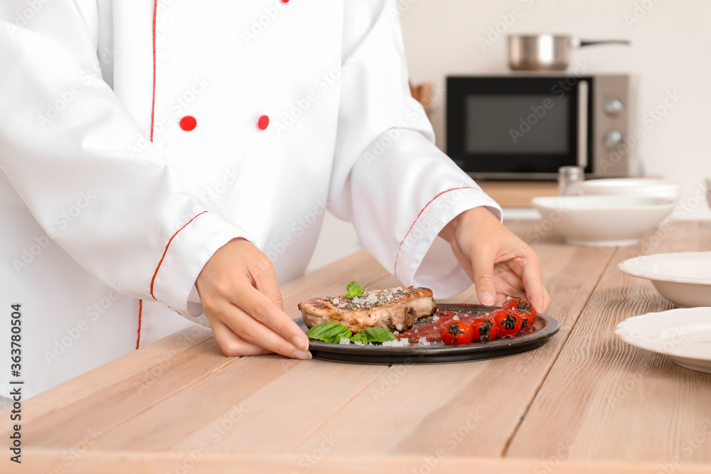 Female African-American chef with tasty dish in kitchen