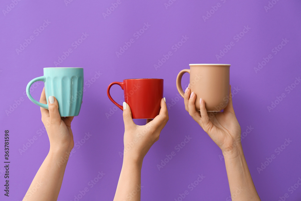 Hands with cups of hot coffee on color background