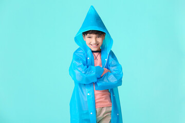 Wall Mural - Cute little boy in raincoat on color background