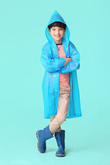 Wall Mural - Cute little boy in raincoat on color background