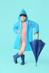 Wall Mural - Cute little boy in raincoat and with umbrella on color background