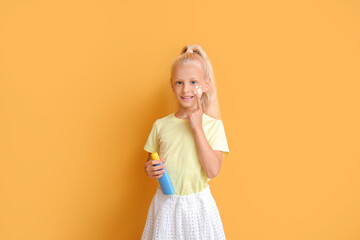 Wall Mural - Little girl with sun protection cream on color background