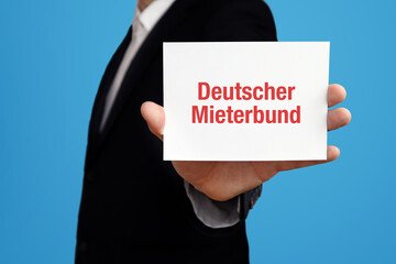 Wall Mural - Deutscher Mieterbund (DMB). Geschäftsmann im Anzug hält Karte in die Kamera. Der Begriff Deutscher Mieterbund steht im Schild. Symbol für Business, Finanzen, Statistik, Analyse, Wirtschaft