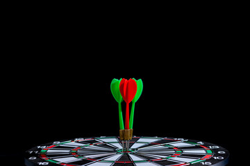 Red and green dart arrow hitting target center is Dart board Isolated on black background