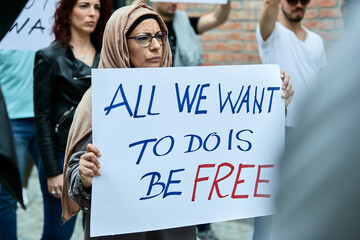 Wall Mural - Muslim woman participating in a protest on city streets.