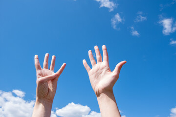 Wall Mural - Close-up of female hands showing nine fingers on a blue sky background. Number nine in sign language. Copy space