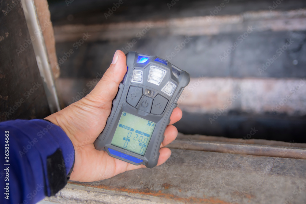 Inspector using the portable gas detector for detect combustible gas , flammable gas , toxic gas and oxygen depletion in a confined spaces before starting work. - obrazy, fototapety, plakaty 