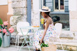 Young smiling african american girl drinking tasty sweet cocktail , amazing relaxing day, tasty lemonade, elegant dress and straw hat, outdoor cafe, summer mood.
