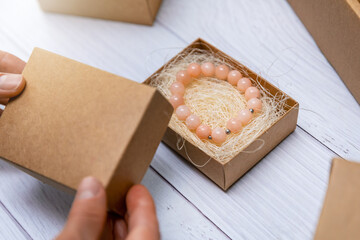 handmade jewelry business - woman packing pearl bracelet in cardboard box for shipping