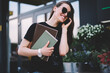 © BullRun - Happy female student with textbooks feeling excited from received good news via telephone conversation about schedule in university, successful hipster girl in trendy sunglasses enjoying cellular call