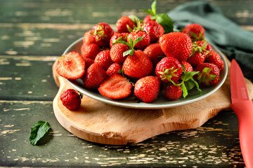 Close up of a plate with freshly picked strawberries on green wooden background