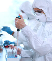 Wall Mural - scientists in protection suits and masks working in research lab using laboratory equipment: microsc