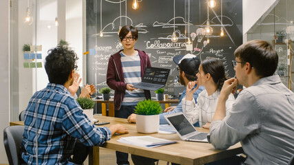 Poster - Charismatic Asian Team Leader Shows Laptop with Data Statistics to Diverse Group of Talented Young Developers, They Start Discussion at Meeting Table. Creative People in Stylish Office Environment.