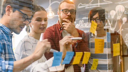 Poster - Diverse Team of Young Developers Brainstorming, They Have Discussion and Use Glass Board and Sticky Papers to Conceptualize Their New Plan. Creative People in Stylish Office Environment.