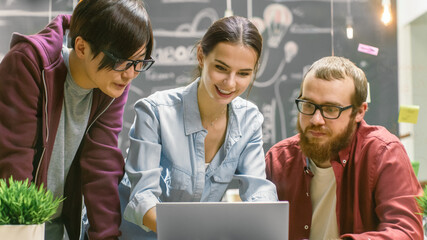 Poster - Three Creative People Have Active Discussion While Using Laptop. Stylish Young People Work in Trendy Environment.