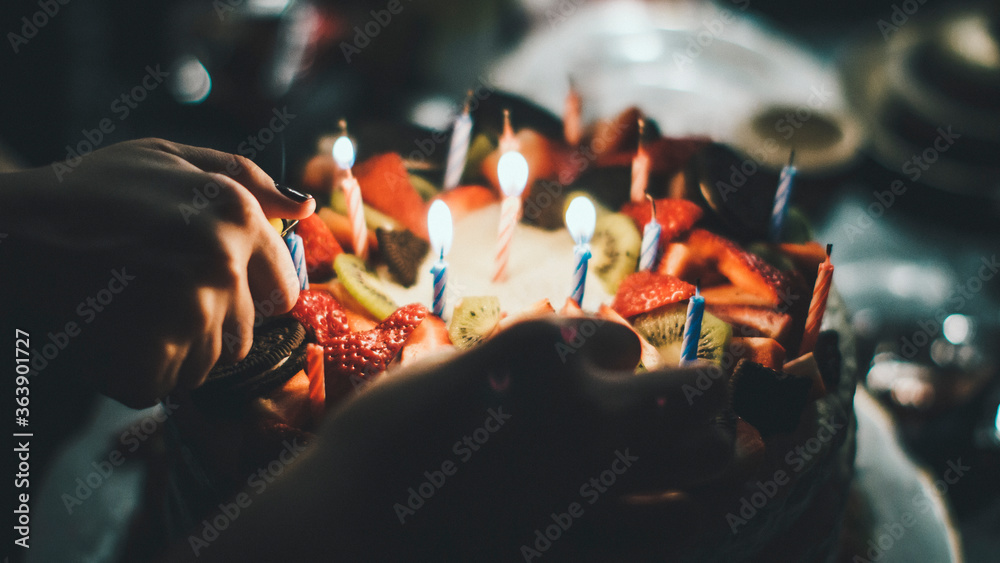 Close-up Of Woman Igniting Candles On Birthday Cake - obrazy, fototapety, plakaty 