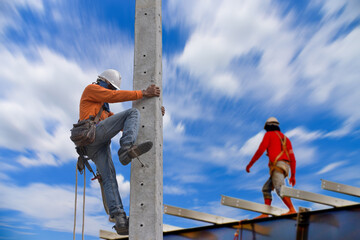 Electricians climbing work on electric power pole on blue sky background