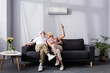 © LIGHTFIELD STUDIOS - Cheerful senior couple using remote controller of air conditioner on couch