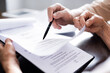 © LIGHTFIELD STUDIOS - Cropped view of elderly couple holding pen and documents with debt collection lettering at home