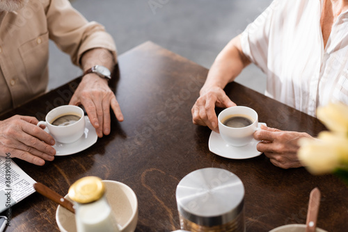 Cropped view of senior couple drinking coffee during breakfast at home