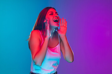 Shouting, calling for sale. Caucasian young woman's portrait on gradient background in neon light. Beautiful female model. Concept of human emotions, facial expression, sales, ad. Copyspace.