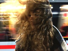 Young Woman With Wind Swept Hair At Railroad Station Against Train