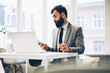 © BullRun - Confident proud ceo with beard reading accounting reports working at digital laptop computer in office building.Male lawyer dressed in formal wear sitting at modern netbook conected to internet