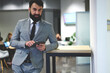 © BullRun - Half length portrait of positive handsome bearded business coach dressed in formal elegant suit using touchpad for browsing information before starting seminar with trainees in coworking space