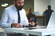 © BullRun - Handsome administrative manager making organization of working schedule noting details sitting in front of laptop computer connected to wireless internet in office, project manager creating strategy