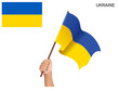 Ukrainian state flag hoisted with a stick held by hand to inflame the spirit of statehood