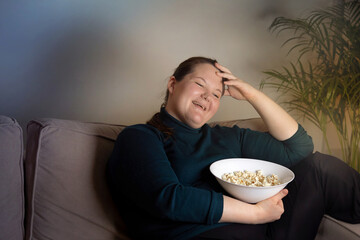 Cheerful beautiful girl sitting in the dark watching TV.