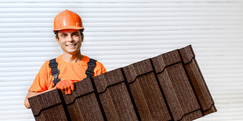 Wall Mural - worker man in uniform and safety helmet holding a piece of metal tile roofing sheet