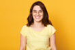 © sementsova321 - Smiling happy woman wearing yellow casual t shirt and eyewear looking directly at camera with happy facial expression, woman standing against yellow wall.