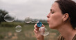 © Ekaterina - The girl blows soap bubbles. A young woman sits in nature and blows soap balls. Face in profile.