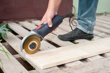 processing the wood with a grinding machine to reveal the texture. Man's hands. Repair or construction work with wood.