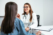 © AH! Studio - Woman doctor examining little girl at hospital checking the sore throat. Pediatrician checking tonsils of a little patient in hospital room.