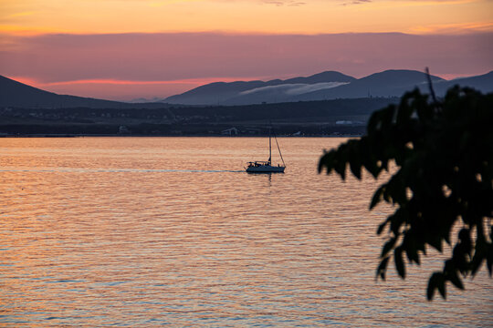 bright orange seascape at sunset, a pleasure yacht against the backdrop of the mountains of the resort city of Gelendzhik. Black sea coast on a warm summer day