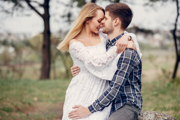 Cute couple in a park. Lady in a white dress. Guy in a blue shirt