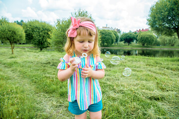 little Beautiful baby Girl blowing soap bubbles in the city park Ureki. Ecology and Nature outdoors. Hot sunny summer. happy childhood, lifestyle