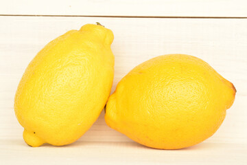 Ripe yellow lemon, close-up, against a background of painted natural wood.