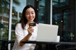 © chayathon2000 - Asian woman shopping online with credit card and laptop computer in coffee shop cafe