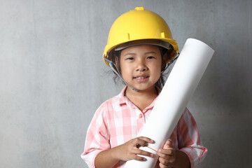 Portrait kid wearing hard hat yellow holding holding a blueprint. To learning and enhance development, little architect.