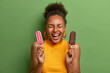 © wayhome.studio  - Unhealhty food and weight loss concept. Positive smiling woman keeps eyes closed and laughs, holds strawberry popsicle and chocolate ice cream, isolated on green background. Summer time, eating