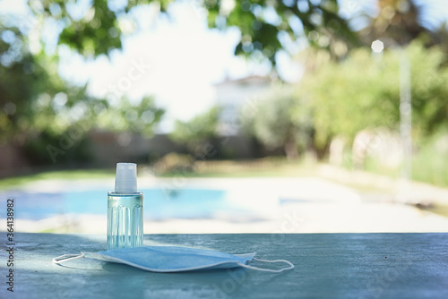 Cuadros en Lienzo Defocused bottom with swimming pool and surgical mask and hydroalcoholic gel with copy space