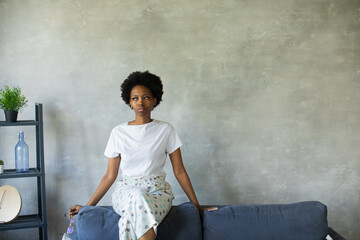 Young Black Woman is Sitting on the Sofa Looking at the window. Black girl disappointed.