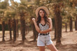 © Dmitry Tsvetkov - Young beautiful woman wearing shorts, shirt and salty hat walking in palms. Tropical resort. Pretty caucasian stylish female model. Life style. Outdoor portrait