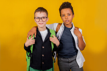 European boy and African American stand in a hug on a yellow background