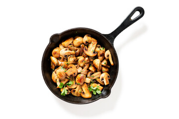 Fried mushrooms with fresh herbs in black cast iron pan isolated on white background.