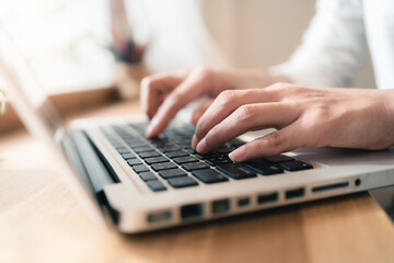 Close up hands of woman using laptop computer working and searching online information with blurry background. copy space of technology business and social distancing concept