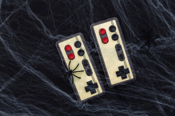 Old retro gamepads on a black background with cobwebs and spiders. Halloween theme. Arachnophobia